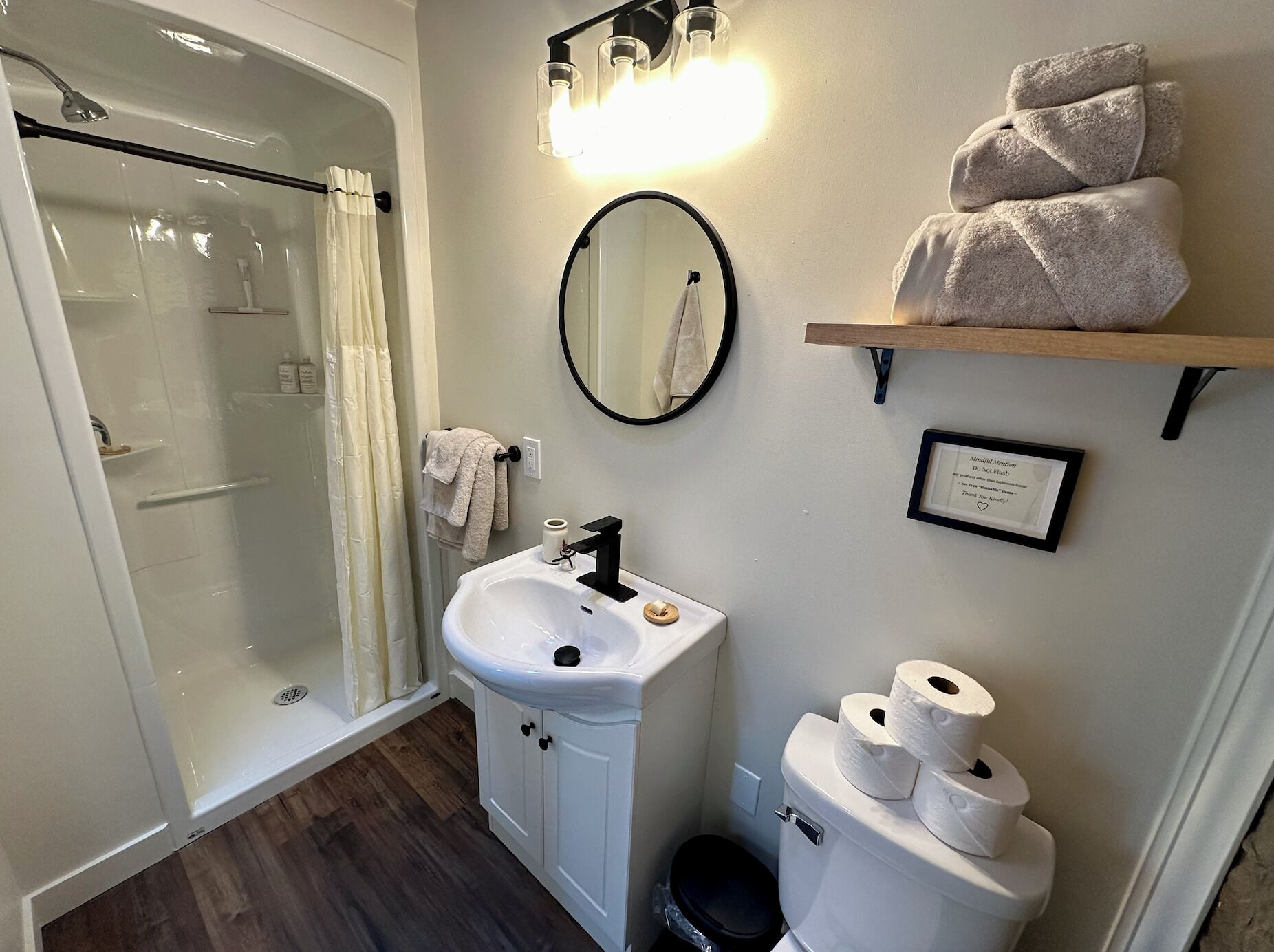 A bathroom with a shower, sink, toilet, and towel rack.