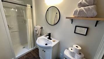 A bathroom with a shower, sink, toilet, and towel rack.