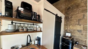 A kitchen with a black microwave, a black refrigerator, and a wooden countertop.