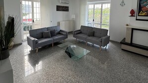 A modern living room with two grey sofas, a glass coffee table, and a large window providing natural light. - Cozy apartment within walking distance of the sea, with pets allowed  (Scalo Ferroviario)