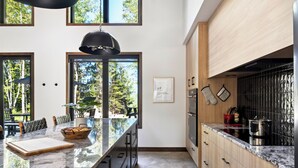Une cuisine moderne dotée d’un grand îlot central, de meubles en bois et offrant une vue sur l’extérieur.