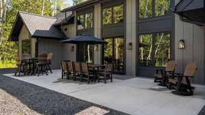 Un bâtiment moderne doté de grandes fenêtres et d’un patio aménagé avec des sièges extérieurs.