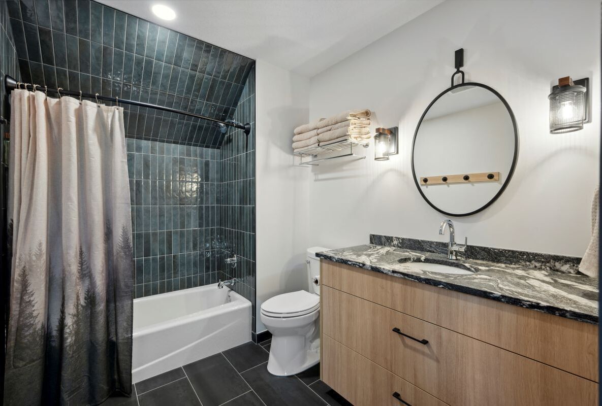 A modern bathroom with a bathtub, toilet, and vanity with a sink and mirror.