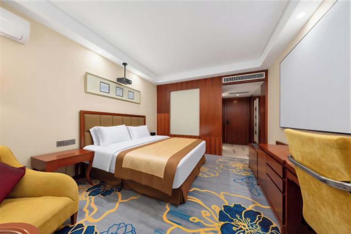 Een hotelkamer met een bed, een bureau, een stoel en een grote spiegel.