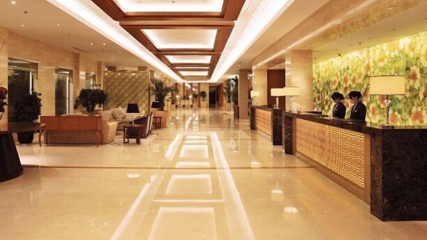 A hotel lobby with a reception desk, seating area, and a long corridor with a patterned floor. - Yangzhou Slender West Lake Huijin Hotel (Yangzhou)