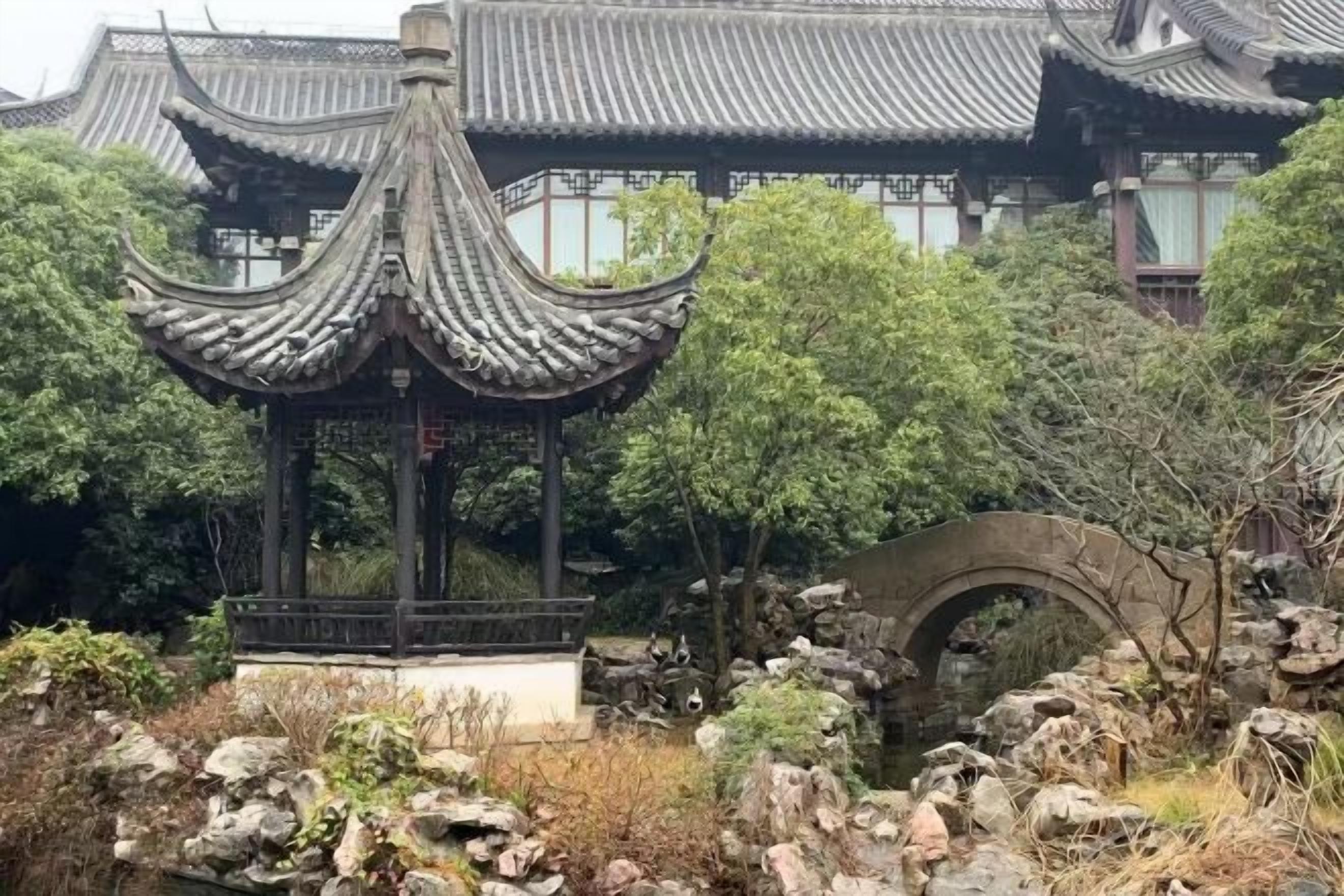 A traditional pavilion with a curved roof, surrounded by rocks and trees.