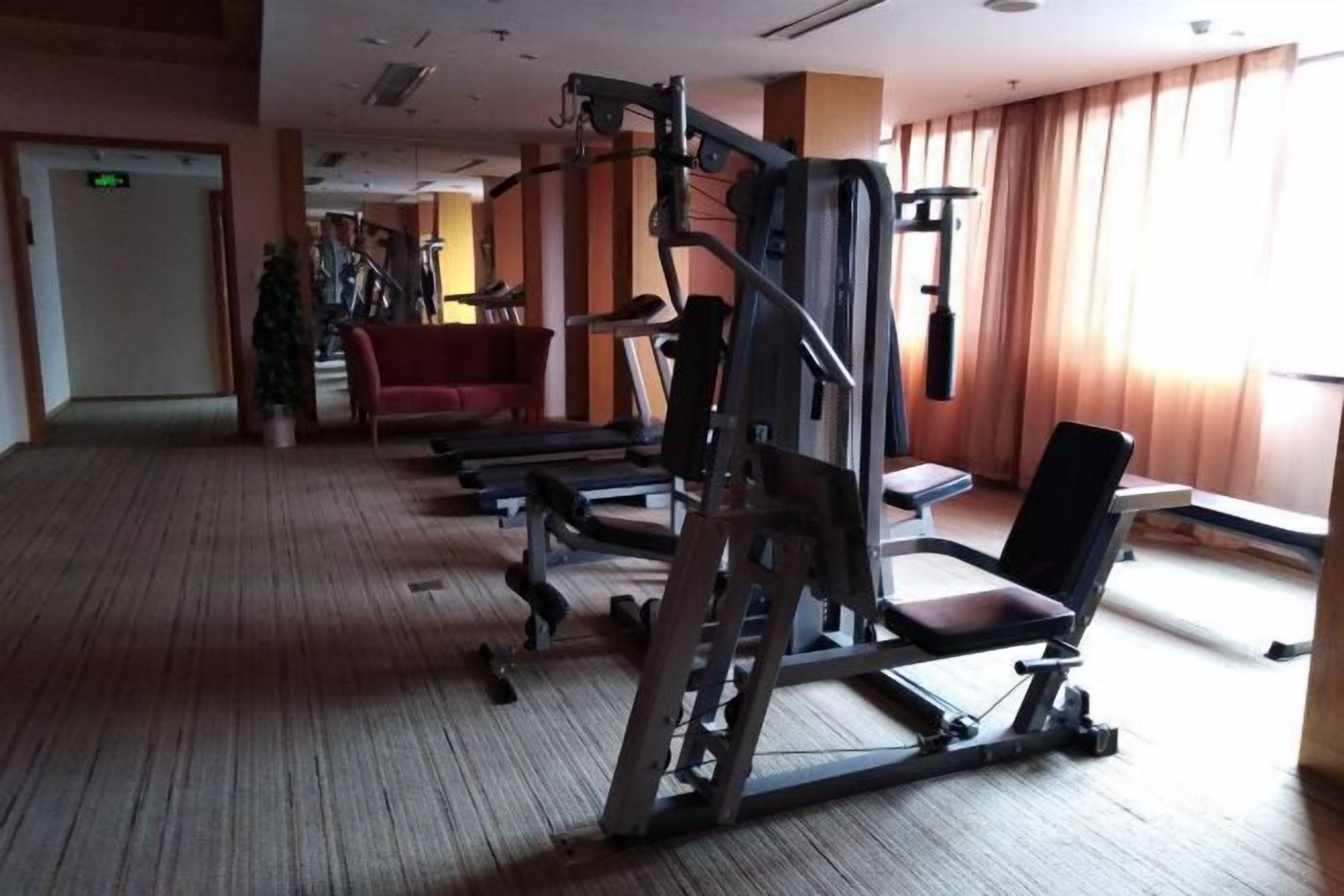 A gym with exercise equipment, a red chair, and a potted plant.