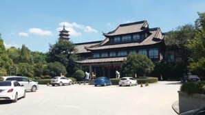 A traditional building with a pagoda-style tower, surrounded by parked cars and greenery. - Yangzhou Slender West Lake Huijin Hotel (Yangzhou)