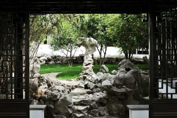 A traditional garden with a rock formation and a wooden gate. - Yangzhou Slender West Lake Huijin Hotel (Yangzhou)