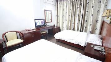 A hotel room with two beds, a desk with a computer, a chair, and a telephone.