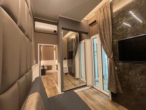 Ein modernes Schlafzimmer mit einem großen Bett, einem Fernseher und einer Schiebetür zu einem Badezimmer.