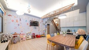 A children's playroom with a wooden table, colorful chairs, and a TV. - Yilan 1955 Bnb Second Branch (Yilan)
