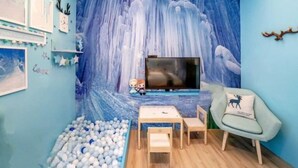 Une pièce dotée d’un grand téléviseur, d’une piscine à balles et d’une fresque représentant une cascade.
