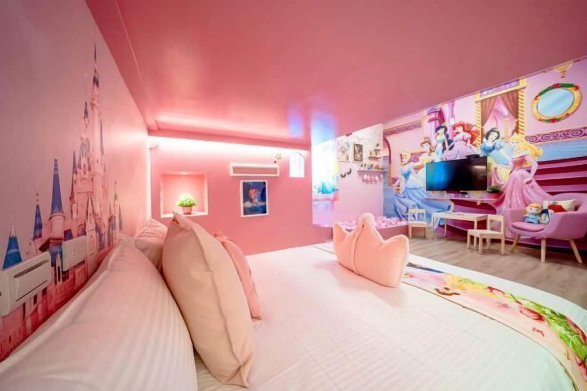 A pink-themed room with a bed, a TV, and Disney princess decorations.