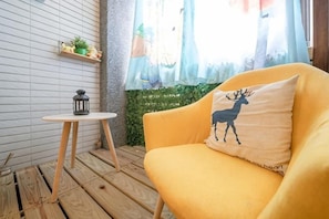 A yellow sofa with a deer pillow, a small round table with a lantern, and a window with curtains. - Yilan 1955 Bnb Second Branch (Yilan)