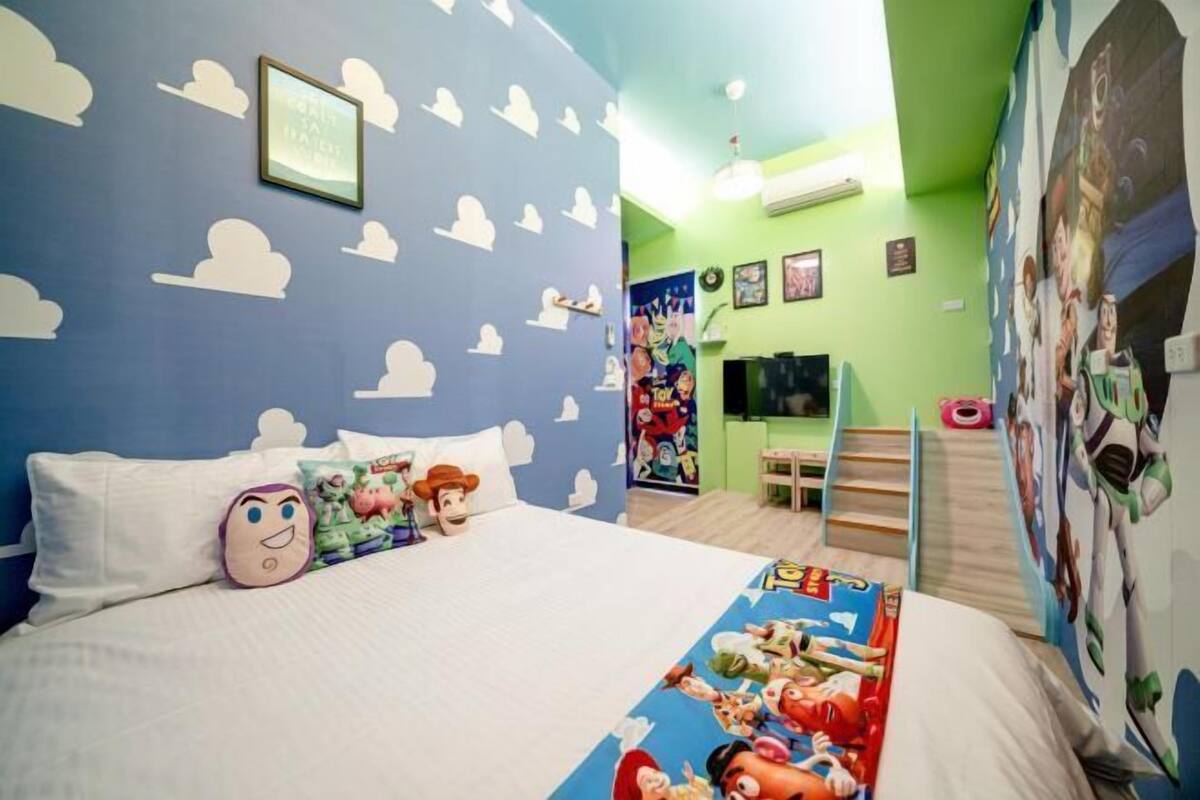 A bedroom with a bed, pillows, a TV, and a poster on the wall.