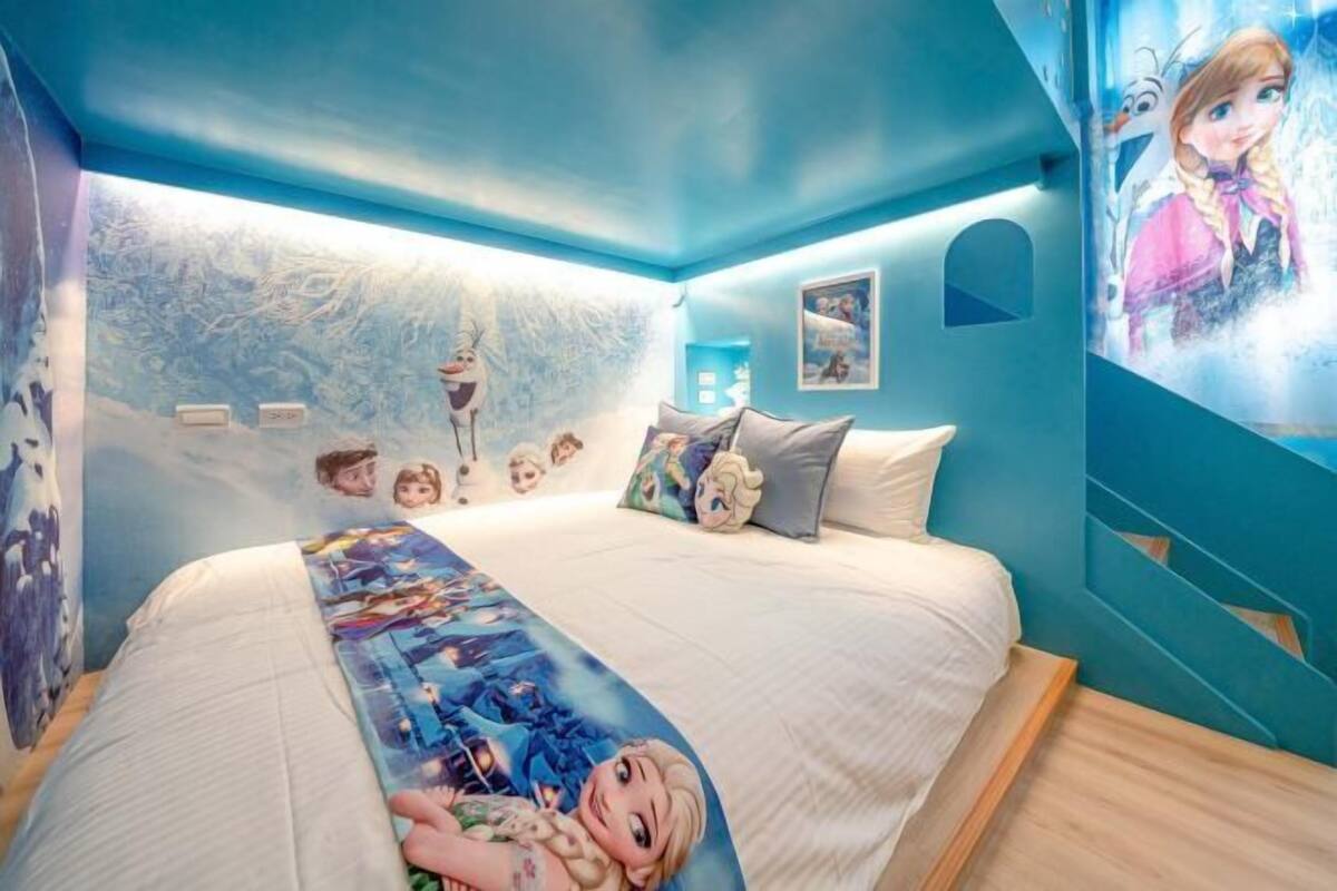 A bedroom with a bed, pillows, and a wall mural.
