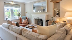 A living room with a fireplace, a sofa, a chair, and a large mirror. - Danes Cottage – Luxury Peak District Retreat (Chapel-en-le-Frith)