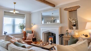 A cozy living room with a fireplace, a chessboard, and a comfortable seating area. - Danes Cottage – Luxury Peak District Retreat (Chapel-en-le-Frith)