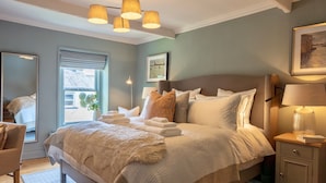 A neatly arranged bedroom with a large bed, bedside tables, a mirror, and a window with blinds. - Danes Cottage – Luxury Peak District Retreat (Chapel-en-le-Frith)
