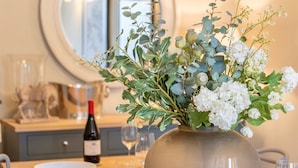 A dining table set with white plates, glasses, and a vase of flowers. - Danes Cottage – Luxury Peak District Retreat (Chapel-en-le-Frith)