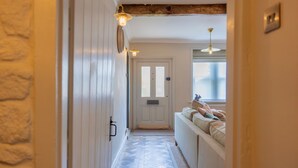 A hallway with a stone wall, a white door, and a window with a view. - Danes Cottage – Luxury Peak District Retreat (Chapel-en-le-Frith)