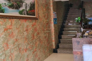 A marble wall with a framed painting, a staircase, and a reception desk. - Dazhou Jindi Hotel (Dazhou)