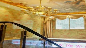 Una habitación con candelabro, ventana con cortinas y una escalera.