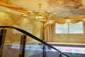 Una habitación con candelabro, ventana con cortinas y una escalera.