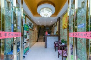 Ein Hotel-Empfangsbereich mit Treppe, Rezeption und Sesseln.