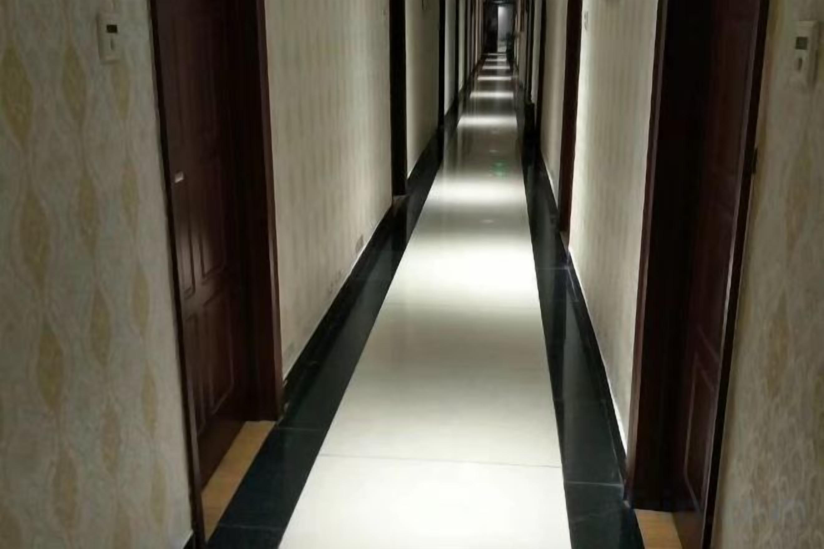 A long, narrow hallway with doors on both sides, leading to rooms.