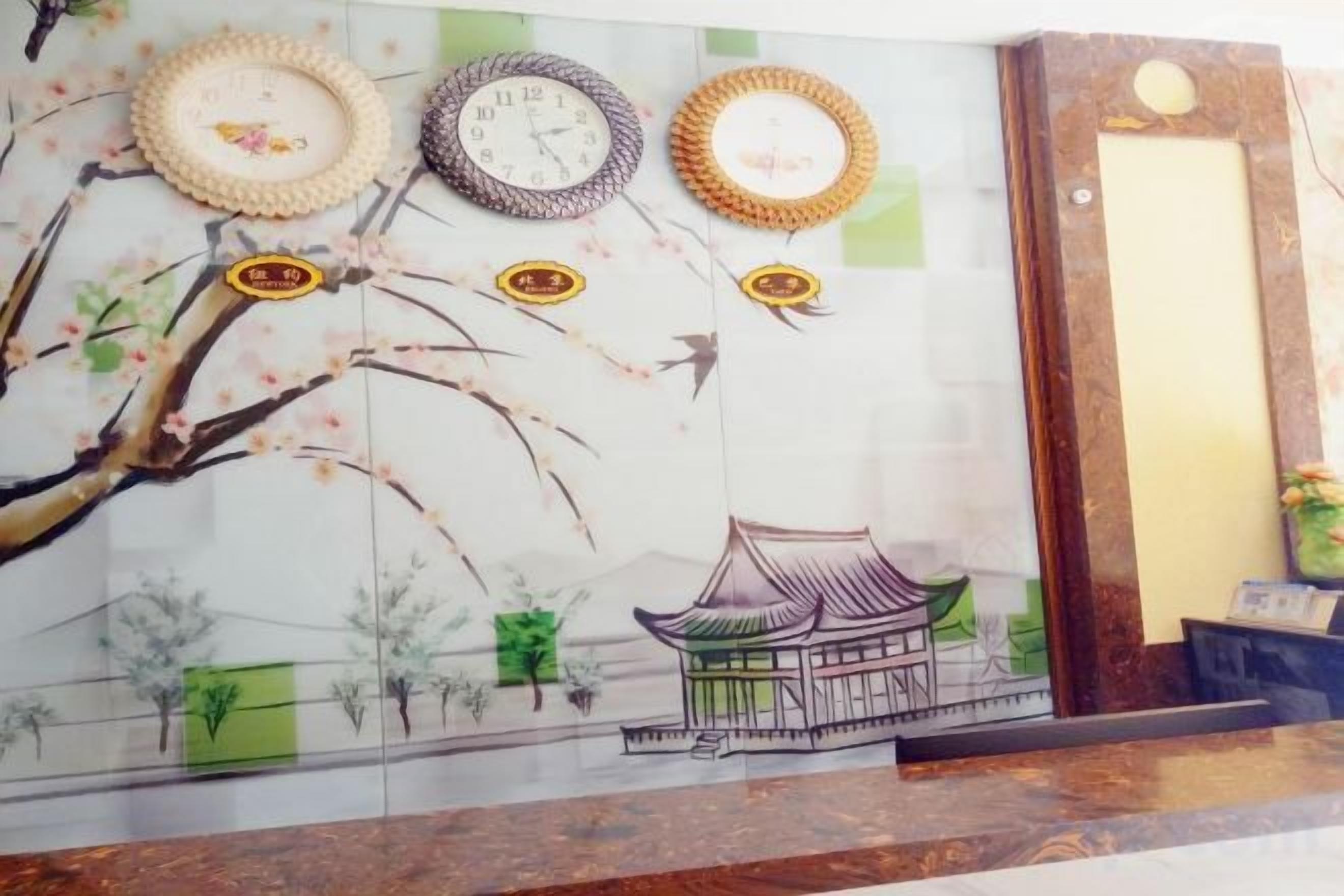 A wall with a mural of a traditional building and trees, a clock, and three wall-mounted clocks.