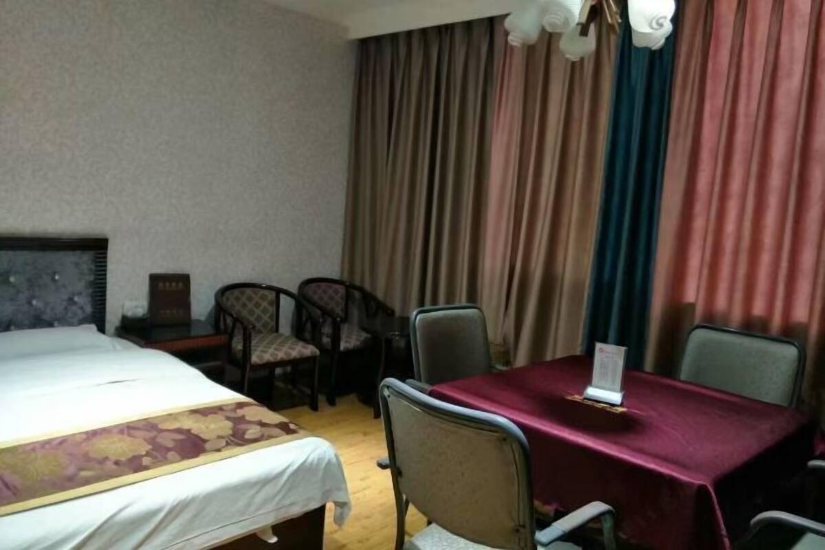 Una habitación de hotel con una cama, una mesa con mantel rojo y dos sillas.