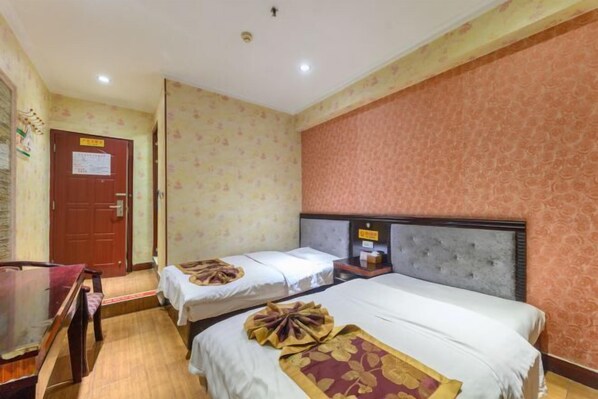 Habitación de hotel con dos camas, un escritorio de madera y una puerta roja.
