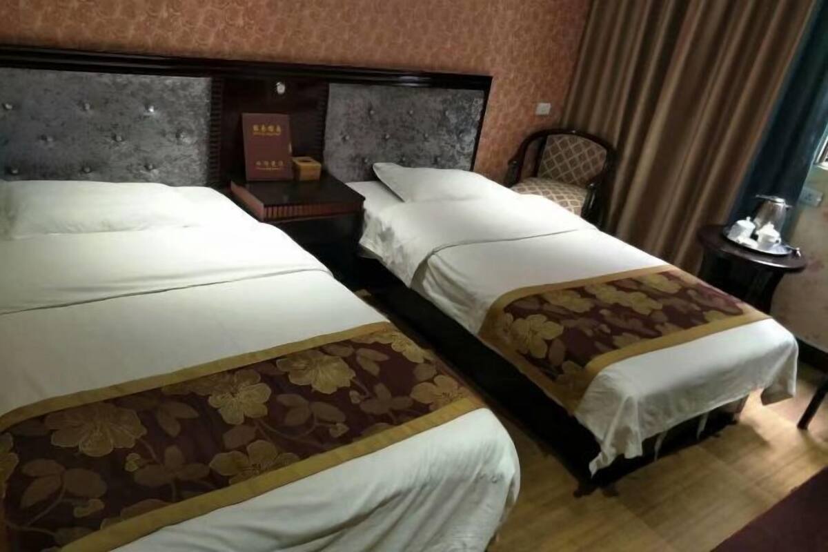 Una habitación de hotel con dos camas, una mesita de noche, una silla y una cortina.