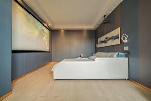 A modern bedroom with a large bed, a projector screen, and a wall-mounted artwork. - Yushan Zheshang Grand Hotel (Jiangjunmiao Square Branch) (Yushan)