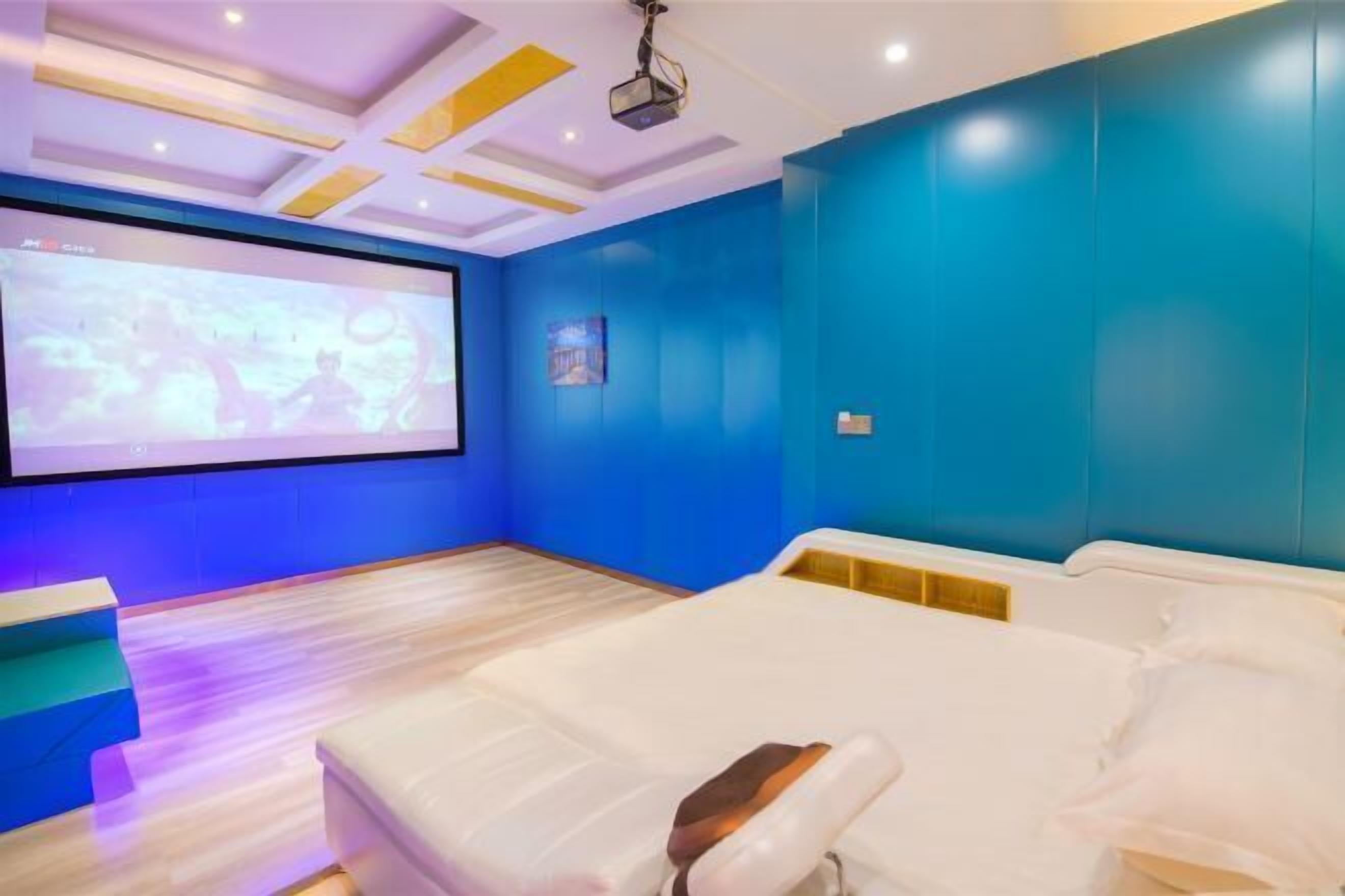 Quarto com uma cama, tela de projetor e parede azul.