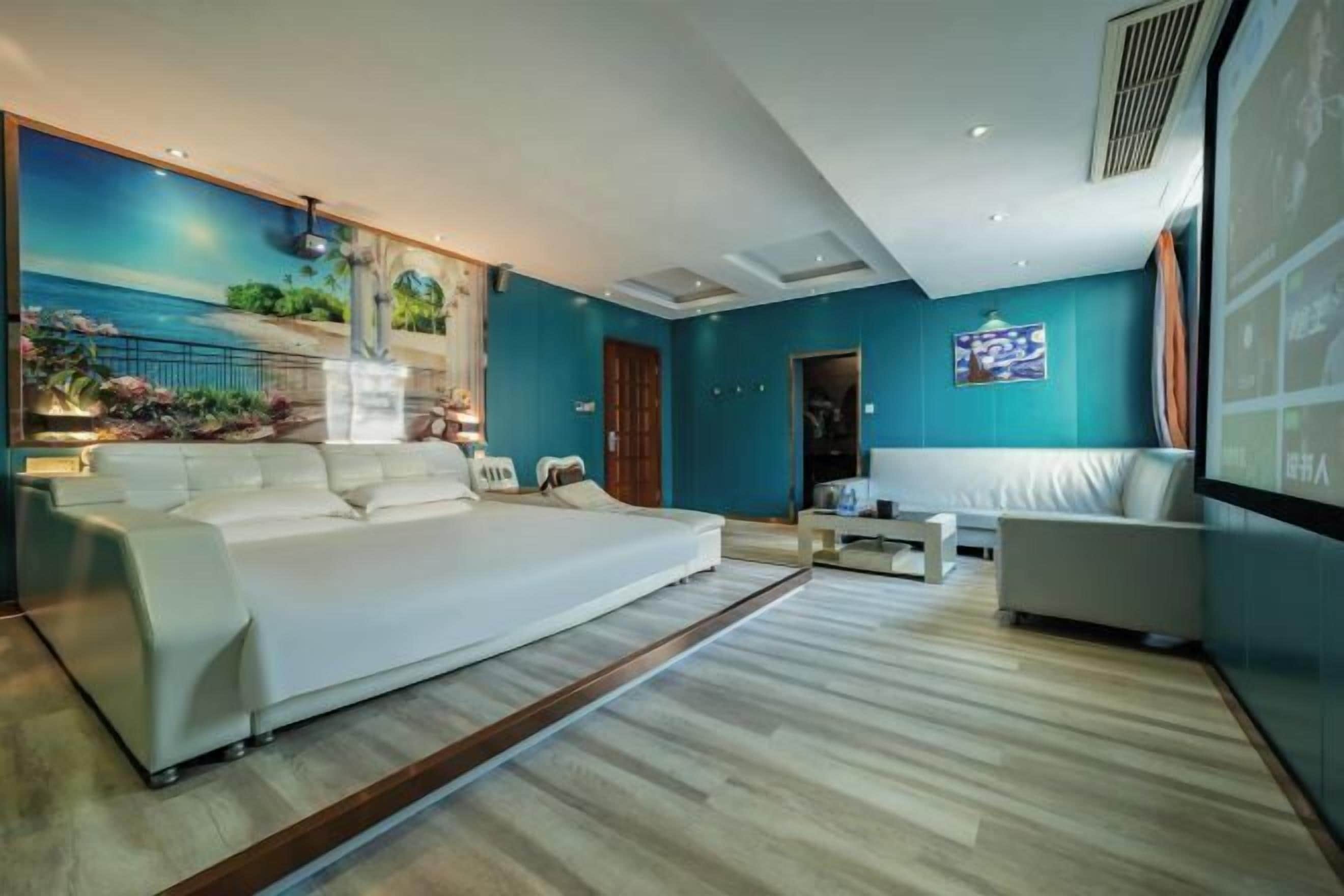 Un dormitorio moderno con una cama grande, un sofá y una mesita. En la pared, un mural que representa una escena de playa.