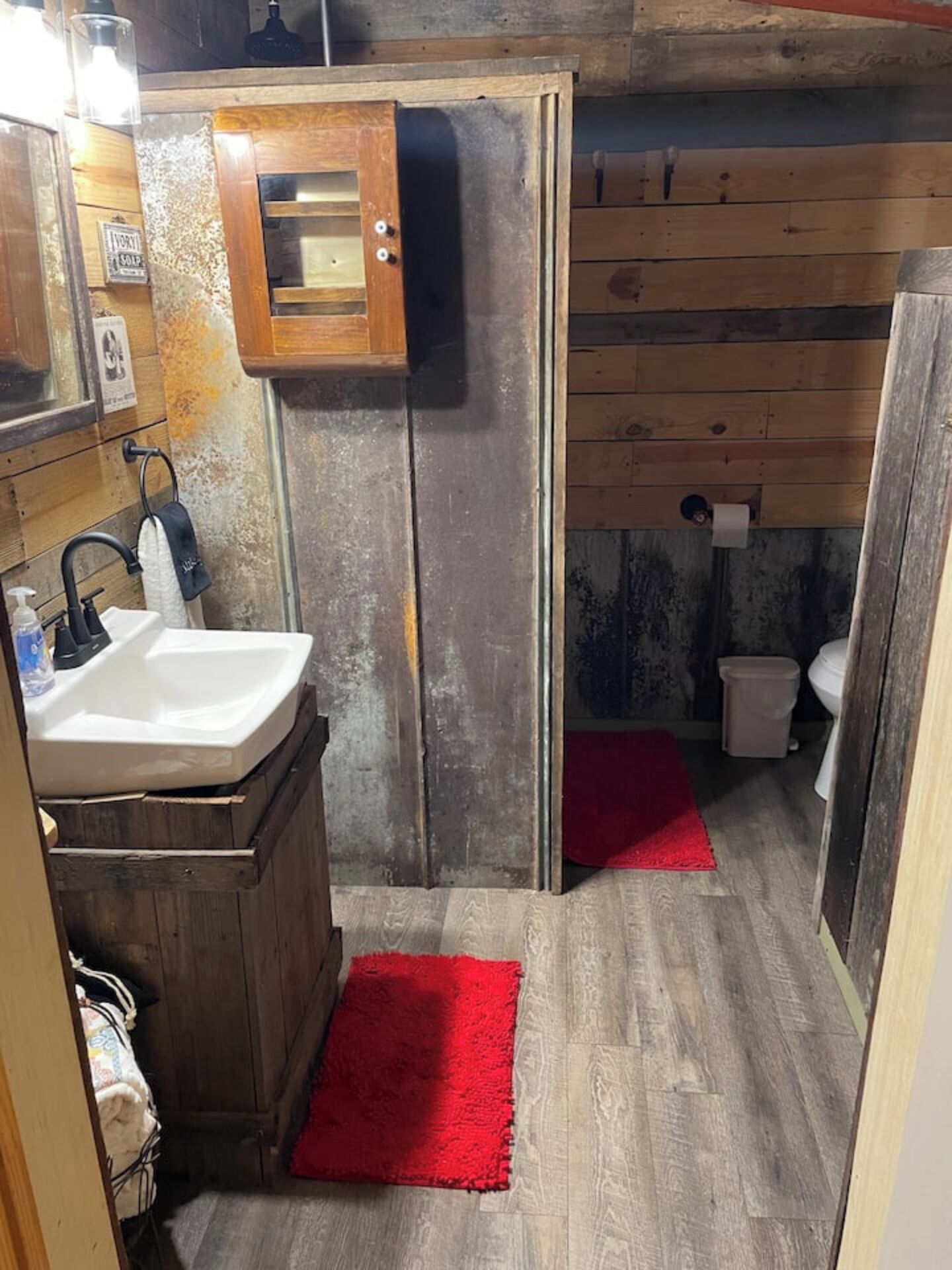 A small, rustic bathroom with a wooden vanity, a sink, and a toilet.