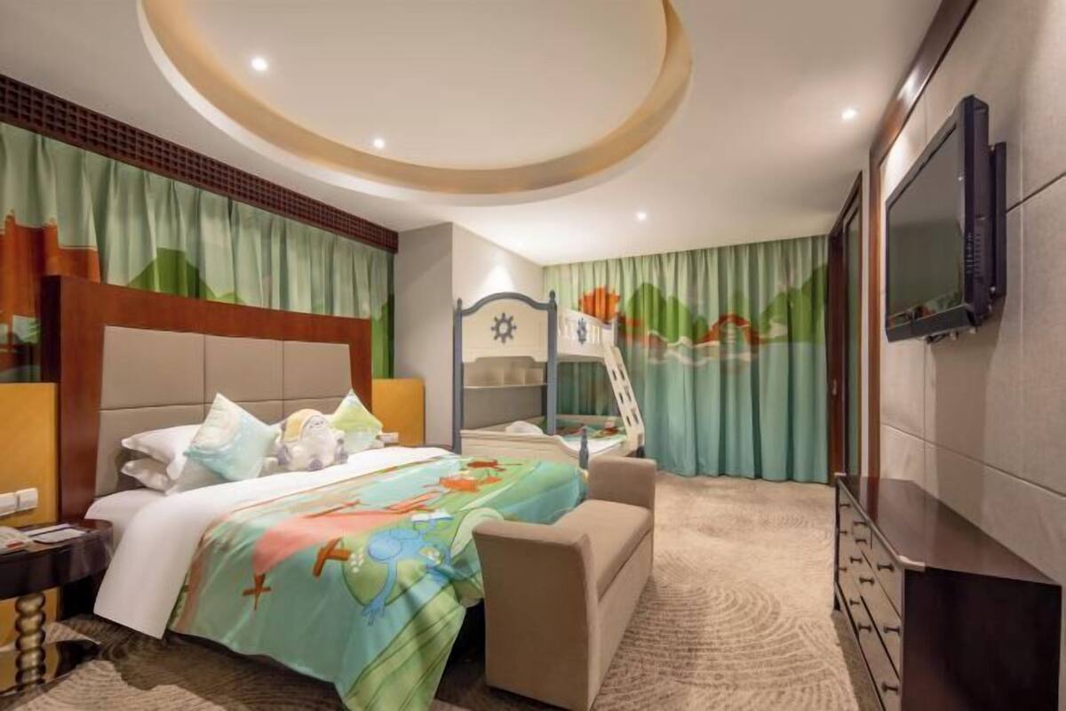 A hotel room with a bed, a desk, a chair, a TV, and a window with curtains.