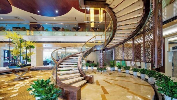 A spacious lobby with a central spiral staircase, multiple levels, and potted plants.
