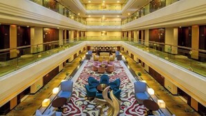 A spacious lobby with a central seating area, glass railings, and a decorative floor pattern.