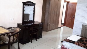 Une chambre à coucher comprenant un lit, une commode en bois, une chaise, un bureau et une armoire.