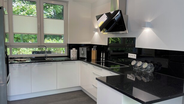 A modern kitchen with white cabinets, a black countertop, and a built-in oven. - Vacation home near Katowice  (Bytom)