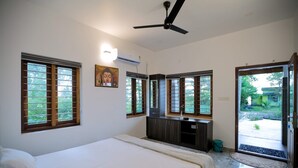A bedroom with a bed, a ceiling fan, a TV, and a window with a view of greenery. - Dolphin turf  - Beach front cottage, relaxing on the wide white sandy beach  (Cherthala)