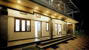 A modern house with a covered porch, large windows, and a tiled patio. - Dolphin turf  - Beach front cottage, relaxing on the wide white sandy beach  (Cherthala)