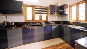 A modern kitchen with dark cabinets, a gas stove, and wooden flooring. - Dolphin turf  - Beach front cottage, relaxing on the wide white sandy beach  (Cherthala)