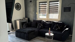 Un salon moderne avec un canapé d’angle, une petite table ronde et un ventilateur de plafond.