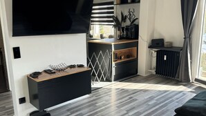 Un salon moderne doté d’un téléviseur à écran plat, d’une machine à café et d’un coin repas aux couleurs noir et blanc.