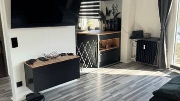 Ein modernes Wohnzimmer mit Fernseher, einer Kaffeemaschine und einer Essecke in Schwarz-Weiß.